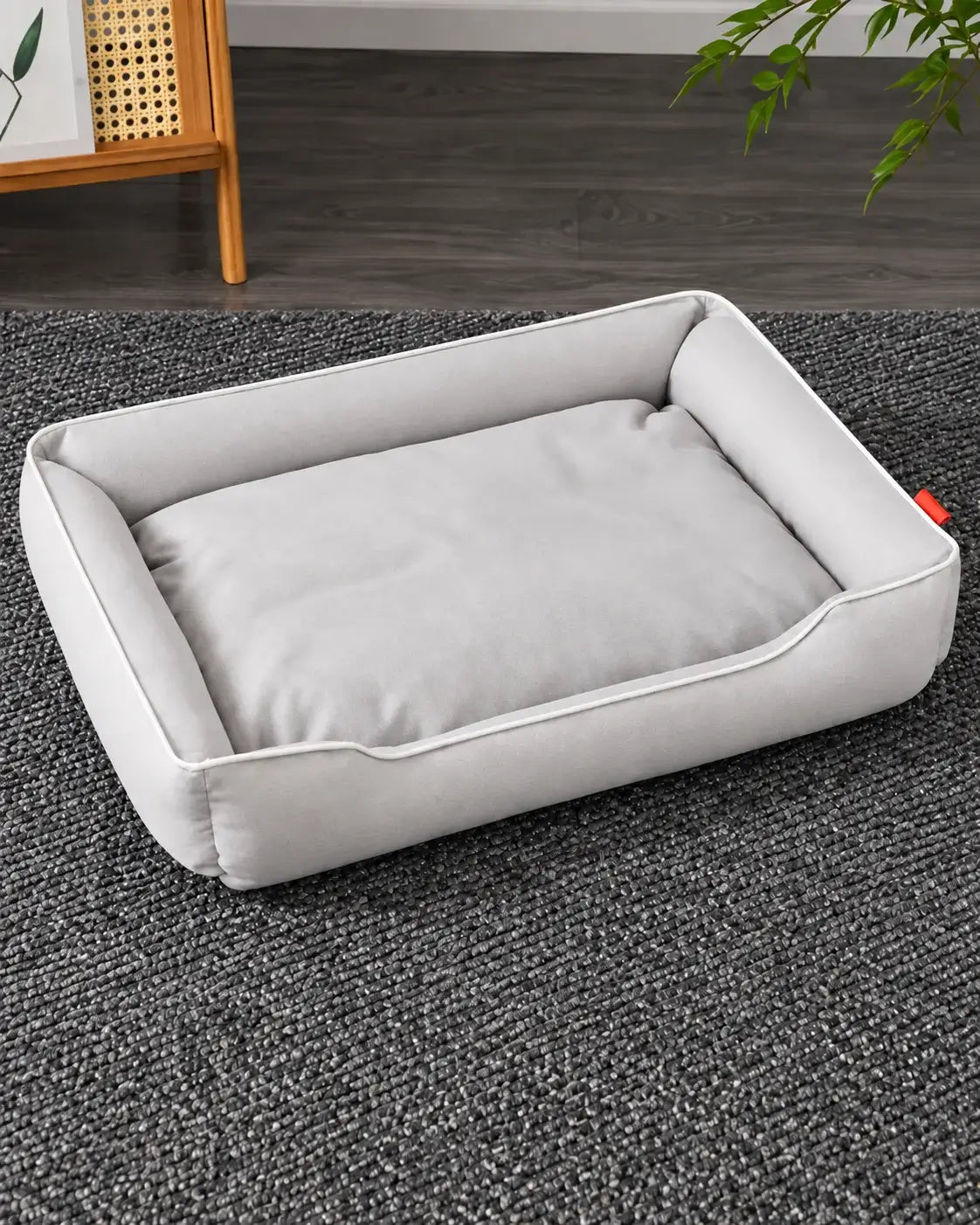 Off-white waterproof dog sofa bed with cream piping on a gray rug