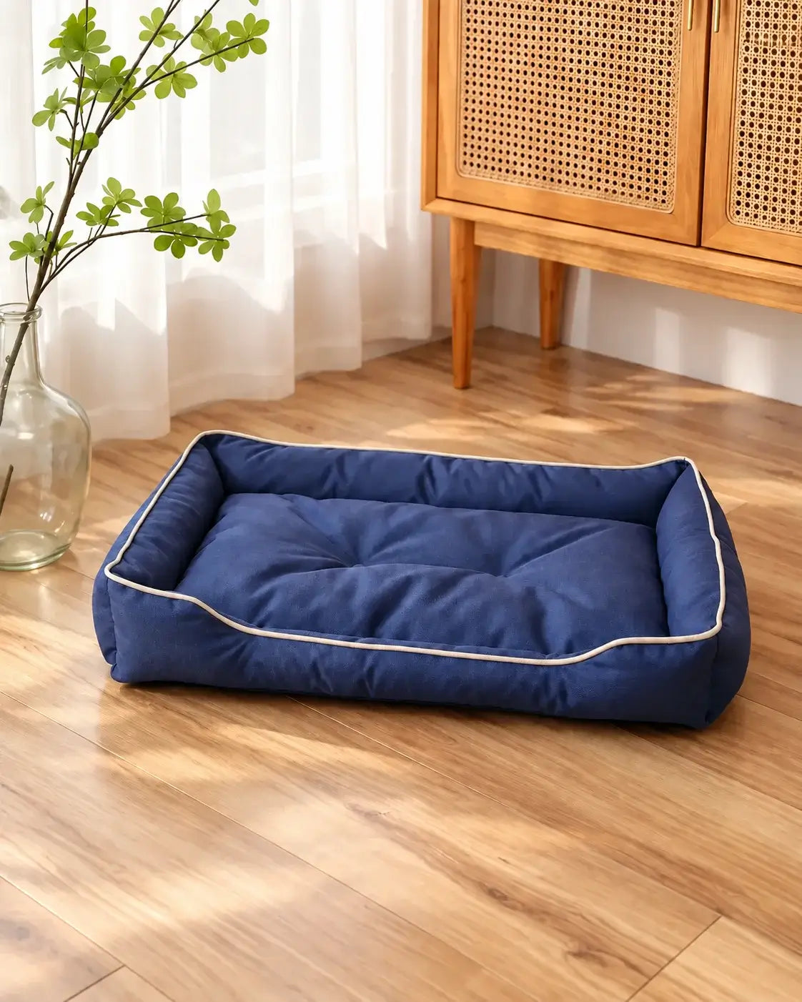 Navy blue waterproof dog sofa bed with cream piping beside a rattan cabinet