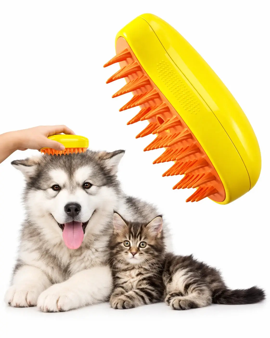 A yellow and orange pet grooming brush is shown with a gray-and-white dog and a tabby kitten on a white background, with a human hand holding the brush above the dog's head.